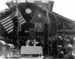 Burma Road dedication ceremony in Kunming, China, on February 4, 1945, during WWII. Review of first convoy (or one of the first convoys) to reach China. General view of the stage and reviewing party, with American and Chinese dignitaries, soldiers, and civilian VIPs. An American band plays, and an honor lines on both sides of the center carpet stand in formation.  Official dignitaries at the ceremony included, on the Chinese side, such figures as General Lung Yun, Governor of Yunnan Province,  Gen. Wang Yu-