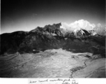 Jade Dragon Snow Mountain (玉龙雪山) with a capping of snow in Yunnan, China, in January as seen from passing American airplane during WWII.  Farm fields and (possibly) rice paddies below.