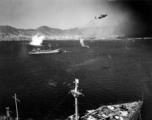 B-25 pulls up after run on Japanese shipping in Hong Kong harbor, while the photographer's B-25 scims just above Japanese cargo ship.