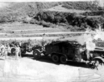 GIs and Chinese soldiers chat near a large Chinese transport truck towing a camouflaged artillery piece in SW China during WWII. 