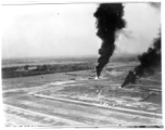 Japanese planes burning in revetments at Chiang Mai air base, Thailand. Note scattered puffs of dust on ground from machine gun or cannon fire.  22nd Bombardment Squadron.