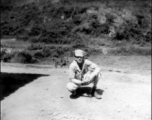 Douglas Runk squatting on road in SW China, during WWII.
