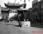 The Golden Horse 金马 archway in Kunming, one of the pair with the Emerald Rooster Archway (金马碧鸡坊) behind the cameraman. A traffic policemen directs traffic from a concrete stand.  In the CBI during WWII.
