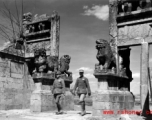 Two Chinese soldiers walk through a ceremonial gate in Yunnan province during WWII.