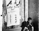 "Little Tiger Joe," Chinese refugee baby adopted by one of the units of the 14th Air Force, is shown here framed by an ancient Chinese doorway, during WWII in China.
