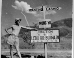 GI leans against sign at junction of Ledo Road and the Burma Road, during WWII.