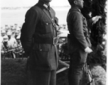 Chinese Lt. General Du Yuming, commander of Nationalist 5th Corps (第五集团军总司令兼昆明防守司令杜聿明) looks at American photographer, with Gen. Wei Lihuang (卫立煌) facing assembled troops, and another person holding a sheet of paper, on stage during rally.