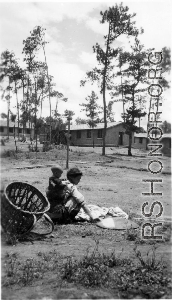 GI explorations of the hostel area at Yangkai air base during WWII: A woman carrying an infant works.
