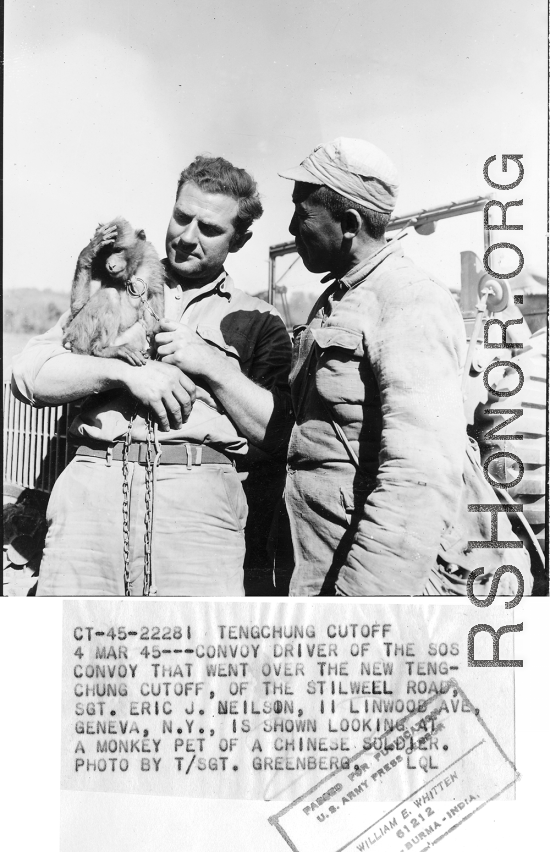 At the Tengchong cutoff: Convoy driver Sgt. Eric J. Neilson, driver of the SOS convoy that went over the Tengchung cut off of the Stilwell Road is shown looking at the pet monkey of a Chinese soldier.  Yunnan Province on March 4, 1945.  Photo by T/Sgt. Greenberg.  Passed by William E. Whitten.