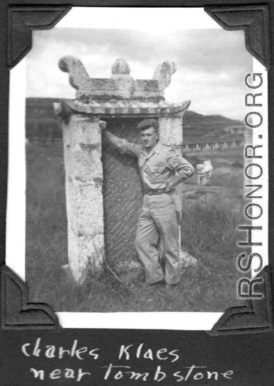 Charles Klaes leans against back of tombstone at base at Yunnan, China. During WWII.