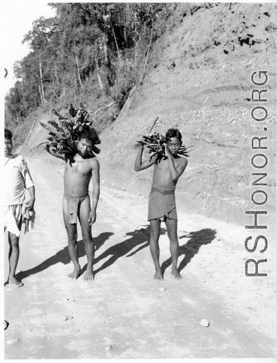 Men carry firewood on road in Burma.  Near the 797th Engineer Forestry Company.  During WWII.