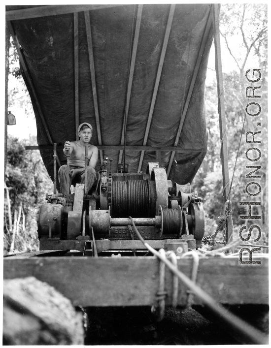 GI pulls logs with donkey engine in Burma.  797th Engineer Forestry Company in Burma.  During WWII.