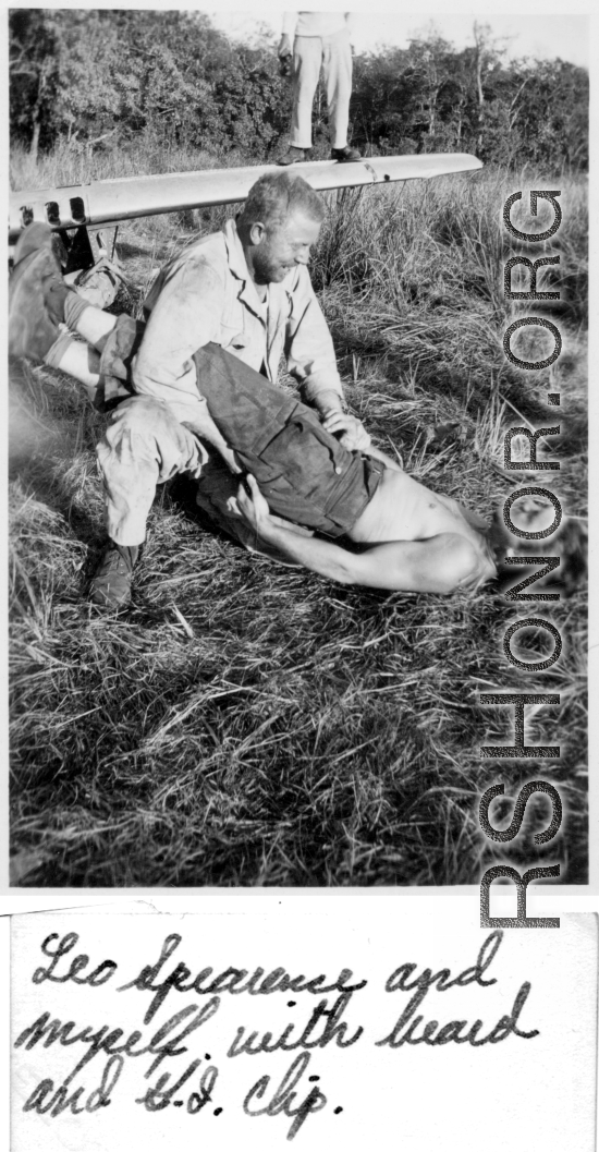 Leo Spearence and John Schuhart (bearded) wrestle on ground. G. I. Clip standing on wing of discarded fighter plane. Likely in Burma. 2005th Ordnance Maintenance Company,  28th Air Depot Group.