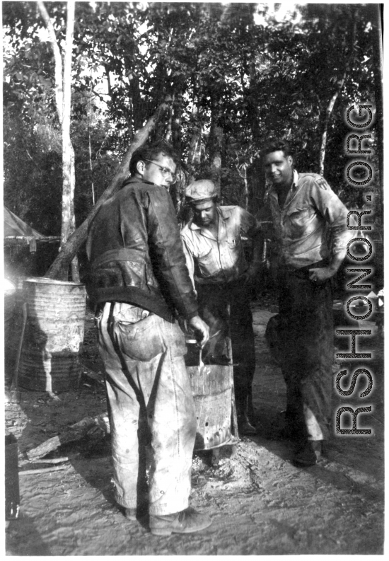 Grease-covered men of the 2005th Ordnance Maintenance Company, 28th Air Depot Group, warming up at burn barrel in Burma. During WWII.