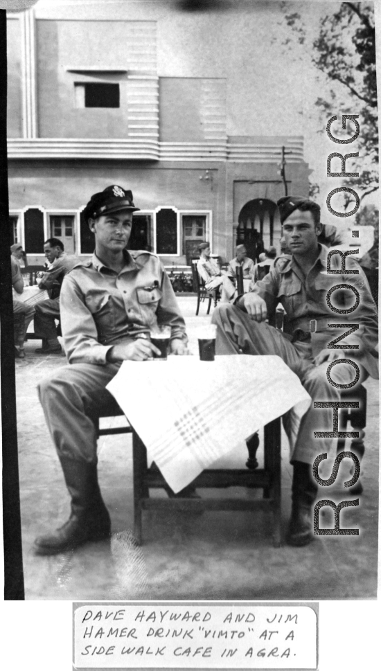 Dave Hayward and Jim Hamer drink "Vimto" (British soft drink) at a sidewalk cafe in Agra. 22nd Bombardment Squadron, during WWII.