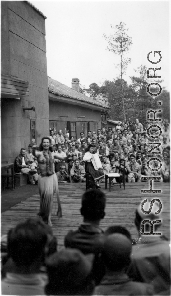 Celebrities (including here Mary Landa dancing, and apparently Ruth Dennis playing instrument) perform on an outdoor stage set up at the "Last Resort" at Yangkai, Yunnan province, during WWII. Notice both Americans and Chinese in the audience for this USO event.