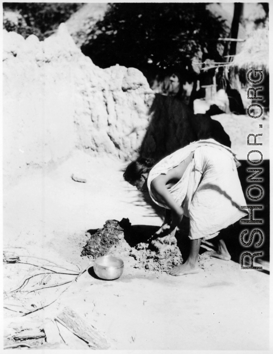 Woman mixing mud or dung and mud with water.  Scenes in India witnessed by American GIs during WWII. For many Americans of that era, with their limited experience traveling, the everyday sights and sounds overseas were new, intriguing, and photo worthy.