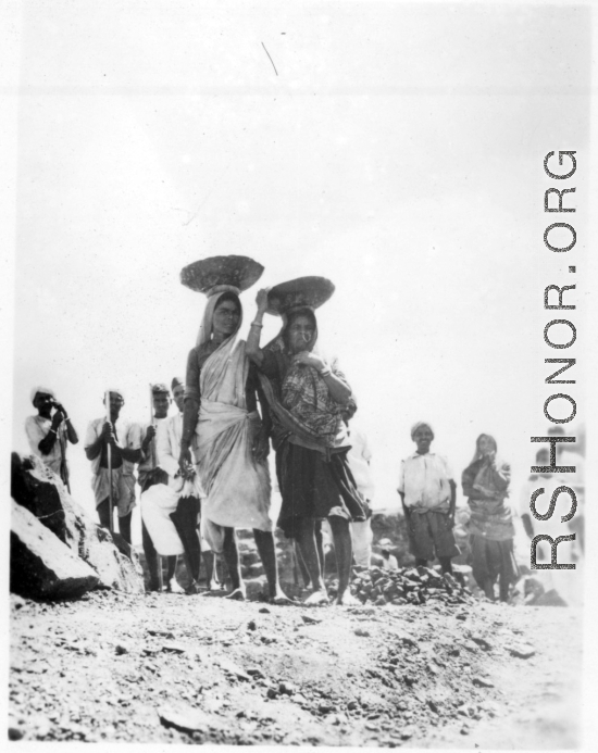 Women carry baskets of crushed stone on their heads.  Scenes in India witnessed by American GIs during WWII. For many Americans of that era, with their limited experience traveling, the everyday sights and sounds overseas were new, intriguing, and photo worthy.