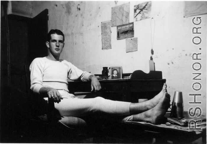 View inside barracks for two GIs in Yunnan, China, during WWII--GI sitting at desk.