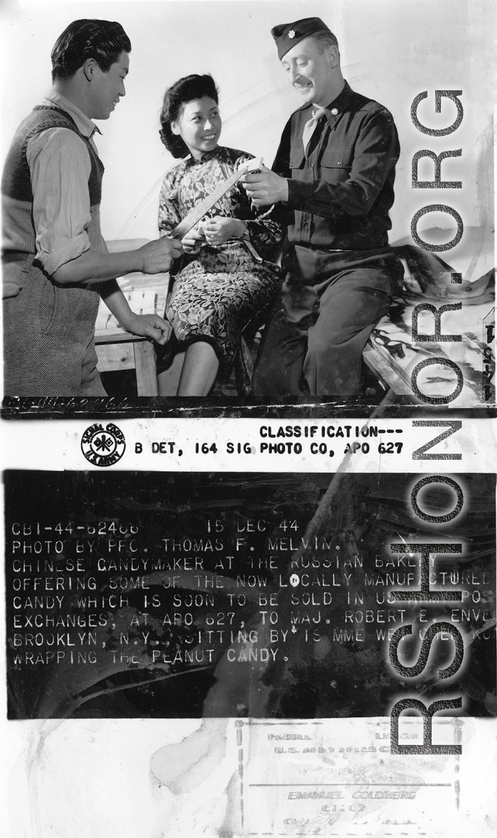 Chinese candymaker at the Russian bakery offering some of the now locally manufactured candy which is soon to be sold in US Army Post Exchanges, at APO 627, to Maj. Robert E. Envell. Sitting by is MME Wei Chen-ko, wrapping the peanut candy. Yunnan Province on December 15, 1944.   Photo by Pfc. Thomas F. Melvin.  Passed by Emanuel Goldberg.