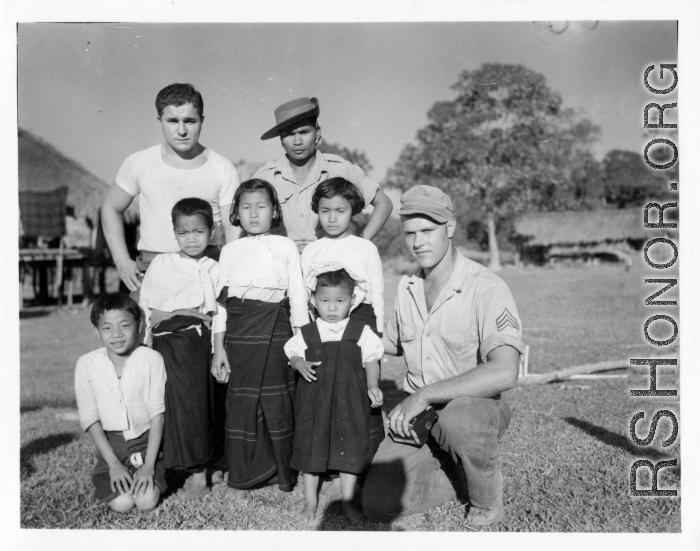 Local people in Burma near the 797th Engineer Forestry Company--GIs pose with local Kachin man and several children in a village.  During WWII.