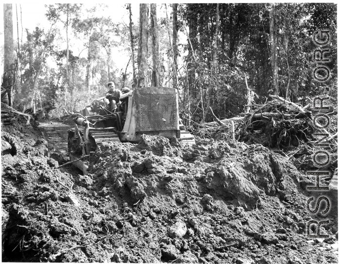 Bulldozer pushing dirt in Burma.  797th Engineer Forestry Company in Burma.  During WWII.