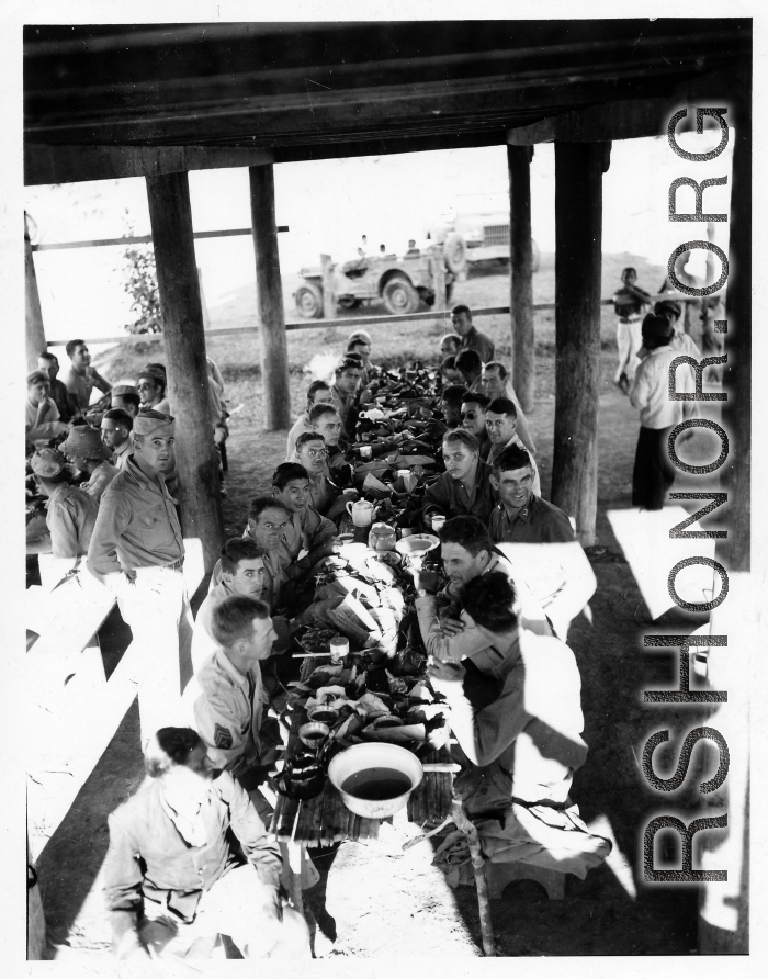 Engineers of the 797th Engineer Forestry Company eating fancy meal in Burma, possibly in the stilt space under a private home.  During WWII.