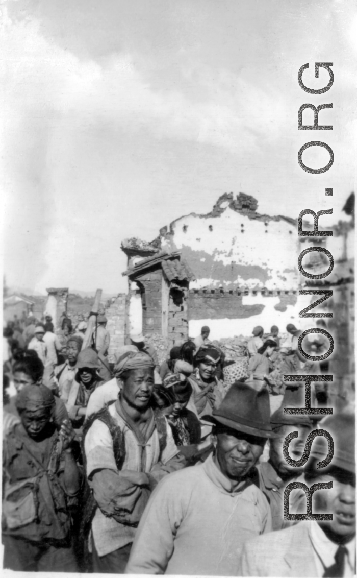 Local people walk by devastated buildings in Yunnan, during WWII.