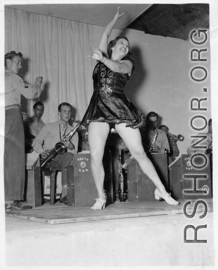 Tap dancer at a USO show in Gushkara, India, during WWII.  The boxes in front of the band players are labeled 748th ROB (748th Railway Operating Battalion).