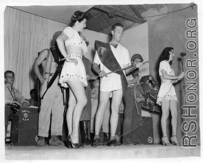 Variety skit at a USO show in Gushkara, India, during WWII.  The boxes in front of the band players are labeled 748th ROB (748th Railway Operating Battalion).