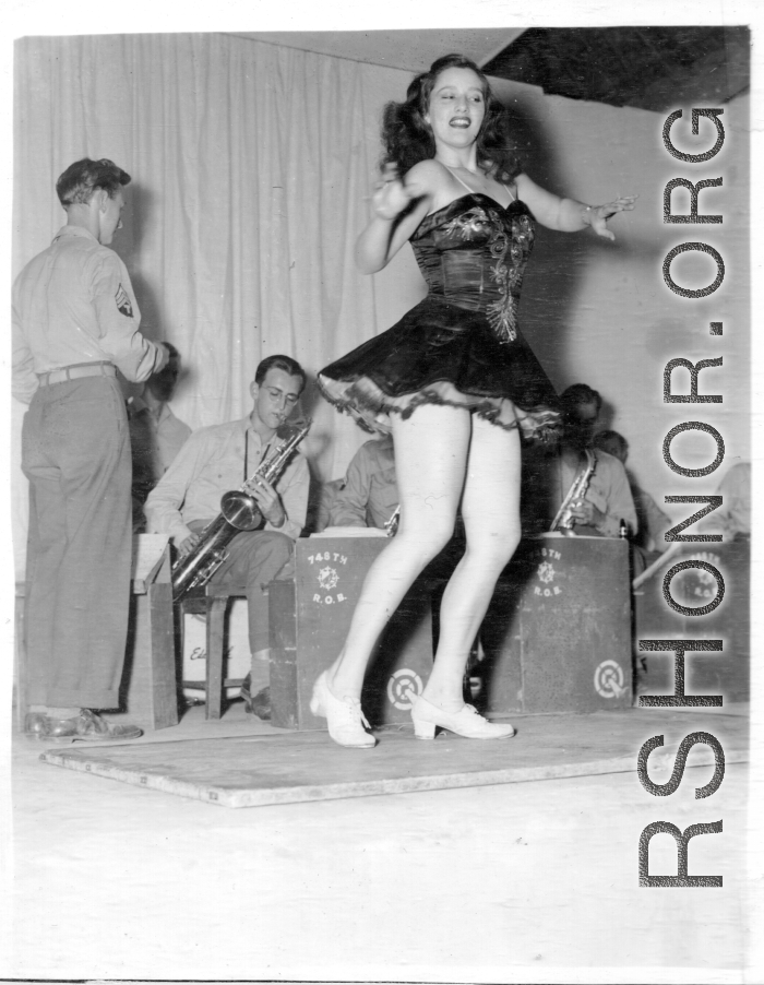 Tap dancer at a USO show in Gushkara, India, during WWII.  The boxes in front of the band players are labeled 748th ROB (748th Railway Operating Battalion).