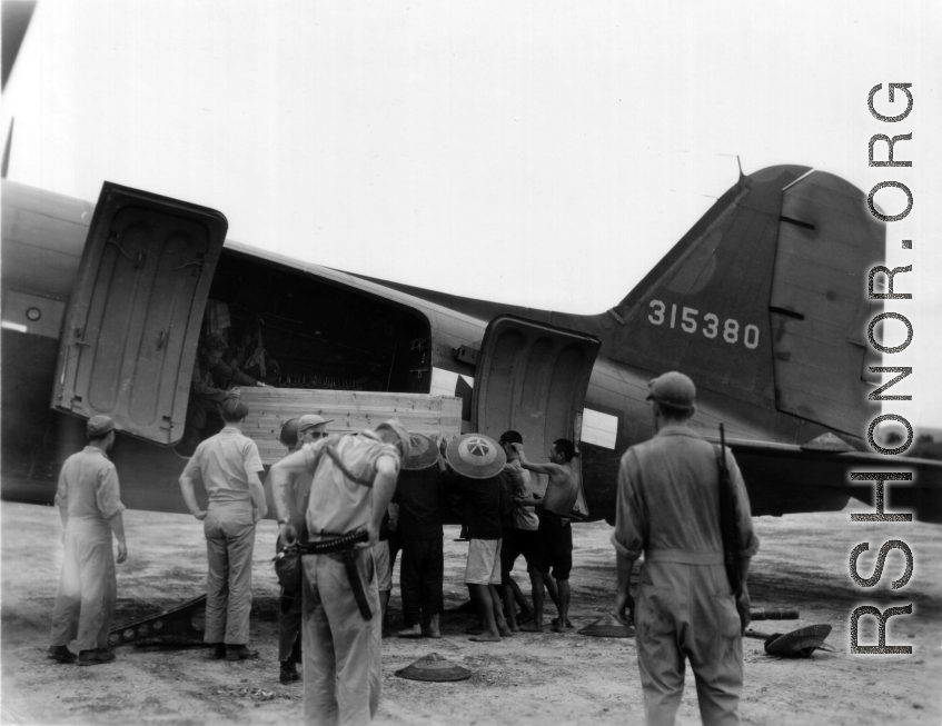 Unloading or loading supplies from C-47 transport plane in China during WWII.