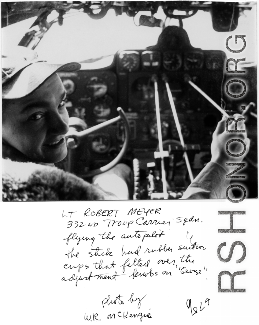 Lt. Robert Meyer in the cockpit of a transport plane (C-46 or C-47 most likely), with sticks on adjustment knobs to act as auto pilot.  332nd Troop Carrier Squadron. In the CBI during WWII.  Photo by W. R. McKenzie.