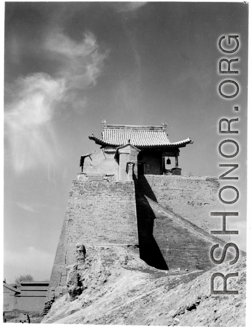 A structure in northern China, elevated on a brick tower set upon the remnants of a town wall. During WWII. This is almost certainly a temple.