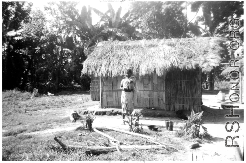 A young girl stands before a hut in India.  Local images provided to Ex-CBI Roundup by "P. Noel" showing local people and scenes around Misamari, India.    In the CBI during WWII.