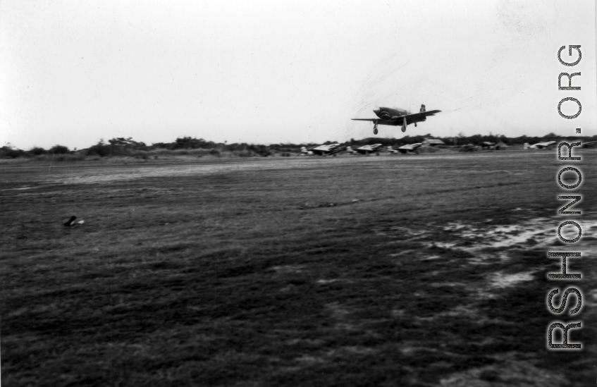 A P-51 fighter plane lands in front of a row of other P-51s in the CBI.