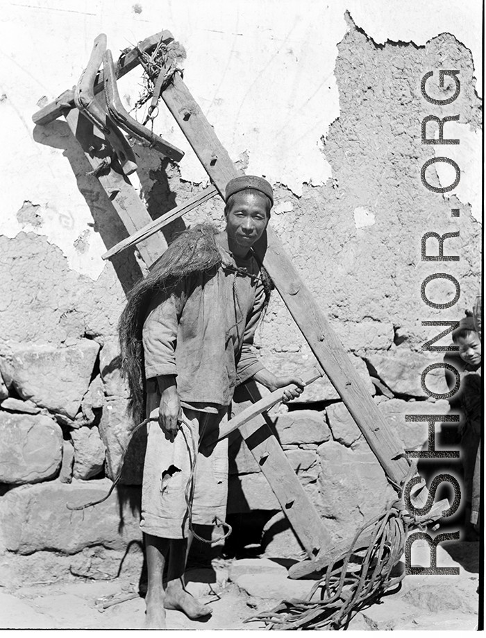 A farmer in a village near Yangkai shoulders a rake used to gather roots and stalks from ground that has been plowed. During WWII.