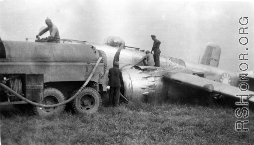 Member of 12th Air Service Group recovering fuel from crashed Nationalist-marked B-25: "Gasoline was a precious commodity in China. All the gas we received had to be flown over the Hump from India into China. This picture shows some members of the 396th pumping gasoline out of the wing tanks of a crashed B-25. With the supply situation of everything having to flown over the Hump nothing was wasted and all serviceable parts were salvaged." Caption courtesy of Elmer Bukey.