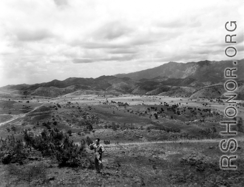 Scenery in China.  Note the young man in work coveralls and holding a carbine in the foreground.  This is probably near Yangkai, Yunnan.