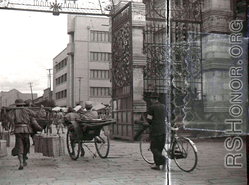 A city gate in Kunming city, Yunnan province, China, during WWII, with a Nationalist soldier riding a rickshaw. 