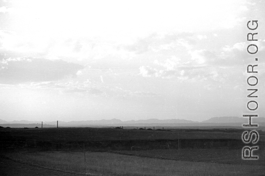 A view across a valley with grave mounds visible. Probably in China, in Kunming province. During WWII.