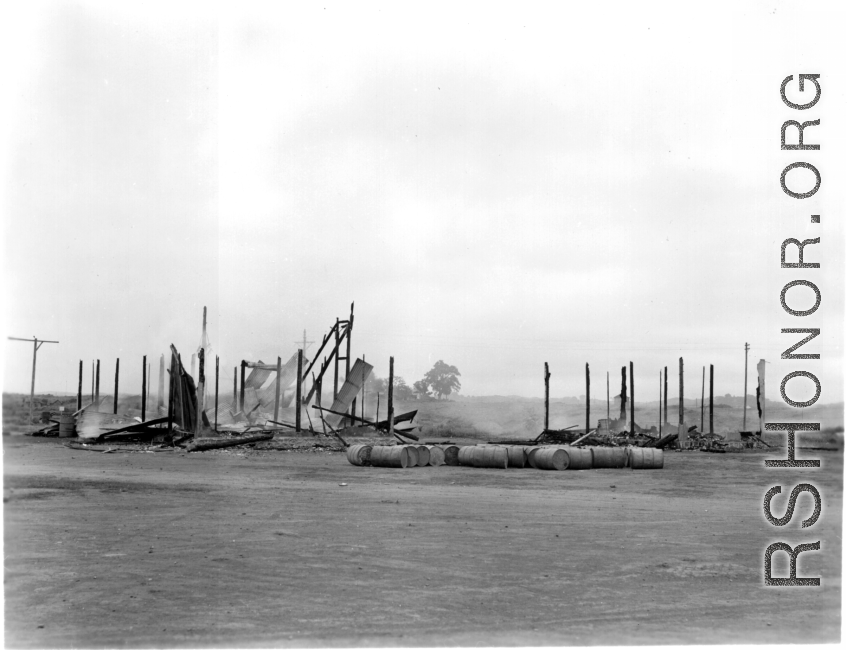 Burned building and fuel barrels at an American base, likely at Guilin, China.