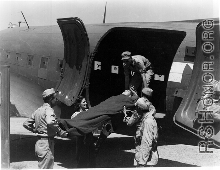 A GI is lifted on a stretcher into a C-47 for transport for medical care in the CBI during WWII.