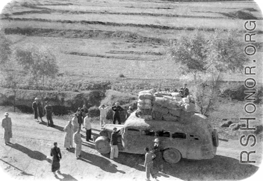 Long-haul bus in northern China during WWII, piled high with cargo. Note the wooden tires on the front, a consequence of war-time limits on rubber use.