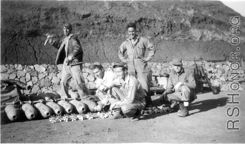 Lemmon, unkn0wn, Red Cummings, Peterson, Gibbs. Arming 100 lb. bombs, and goofing for the camera at the same time, in a revetment. During WWII.  Probably at Yangkai.