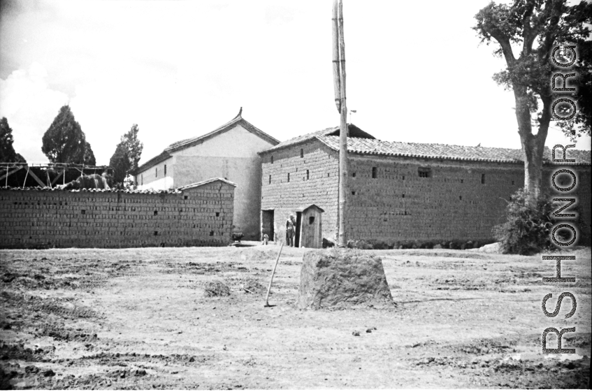 Some large, possibly official, buildings near or on an American air base in Yunnan, China, during WWII. Note the small guard shack at the opening between the structures.