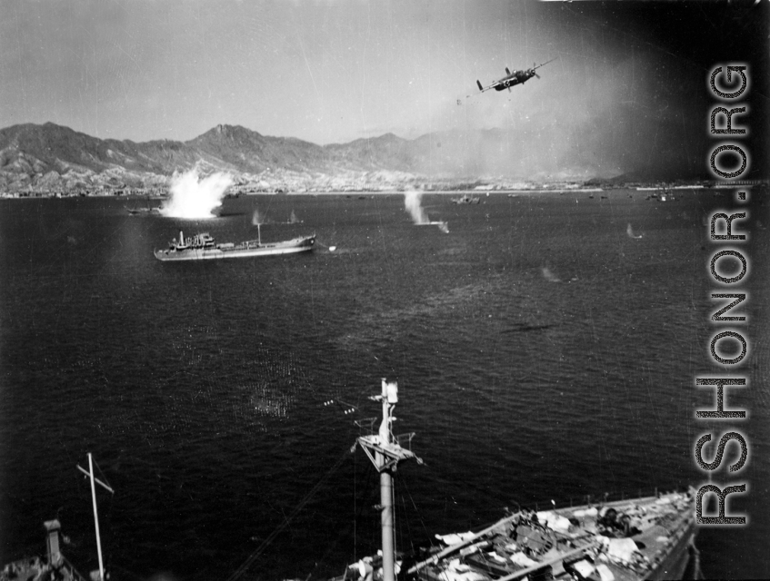 B-25 pulls up after run on Japanese shipping in Hong Kong harbor, while the photographer's B-25 scims just above Japanese cargo ship.