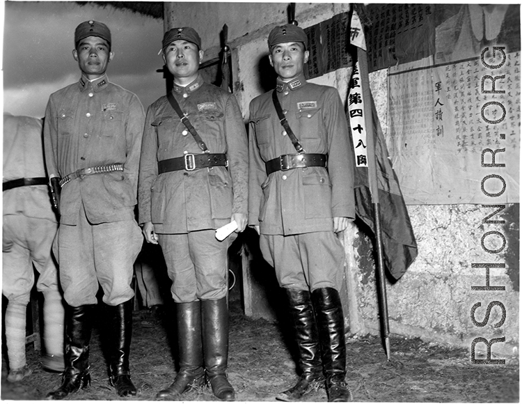 Young Nationalist officers stand before banners for different regiments of the 48th Army Division at rally.