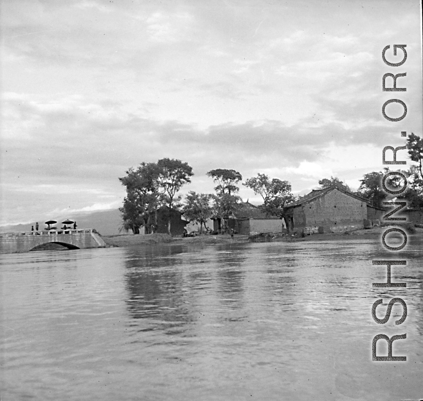 The bridge at Luliang with high water after the rain. During WWI, 1944.  "Luliang (China), vendors on a stone bridge spanning the high water of Nanpan river: A river near Luliang, where in the spring of the year, it became quite high. The arch of this stone constructed bridge forms an almost perfect semi-circle reflection of the river water. [Vendors] had set up stalls on the bridge to sell their wares."