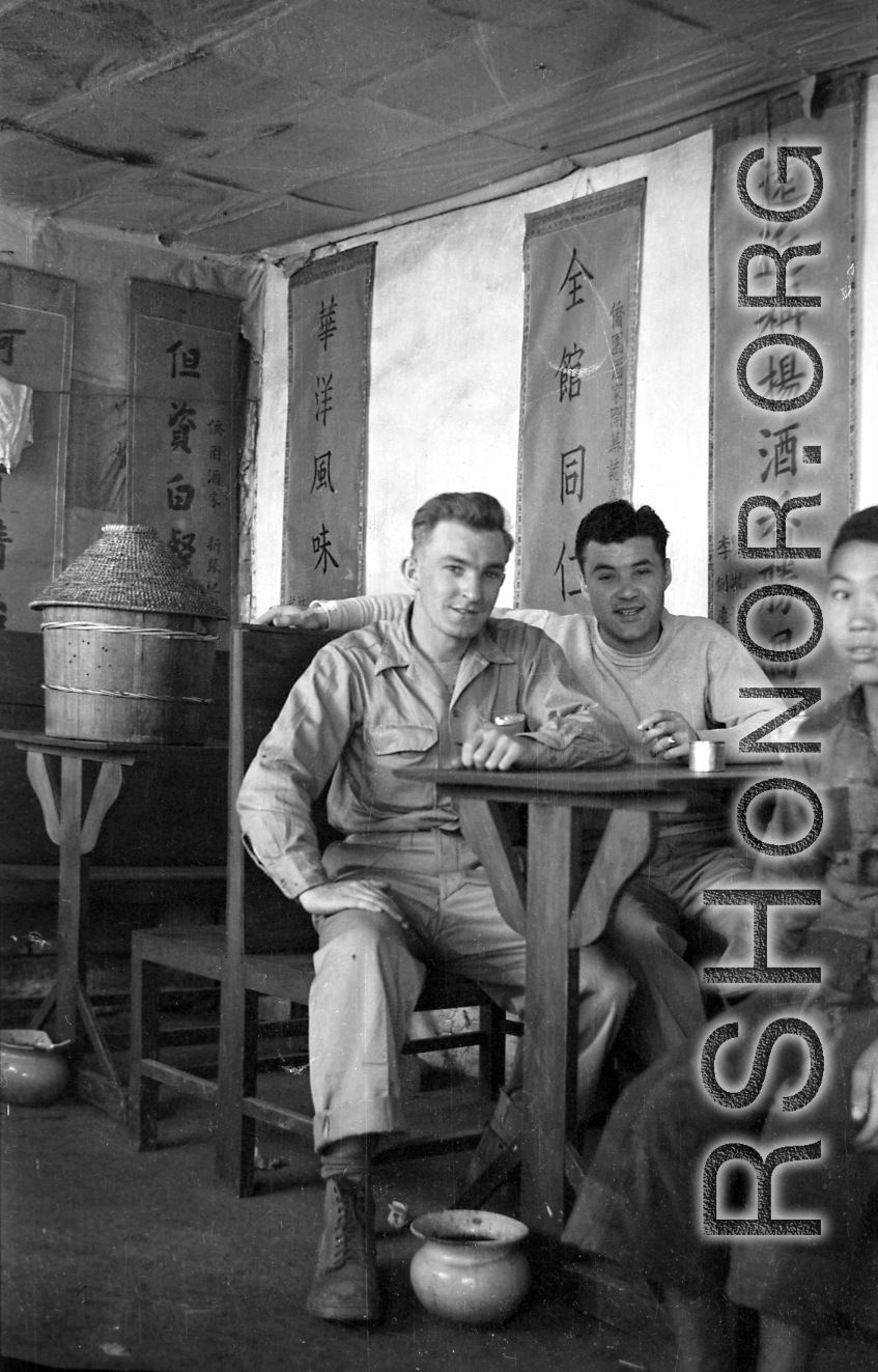 "China, Bert Krawczyk and George Clements sitting at a restaurant table with an unidentified Chinese boy." During WWII.